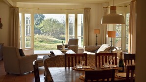 A dining room with a table set for four, a sofa, and a window with curtains. - Large, detached cottage, 5 stars, near the beach, beautiful view. (Buren)