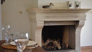 A fireplace with a duck figurine on top, a table with glasses and plates, and a wall socket. - Large, detached cottage, 5 stars, near the beach, beautiful view. (Buren)