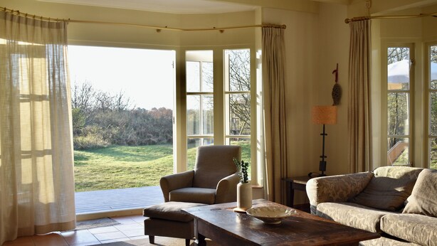 A spacious living room with a large window, a sofa, a chair, and a coffee table. - Large, detached cottage, 5 stars, near the beach, beautiful view. (Buren)