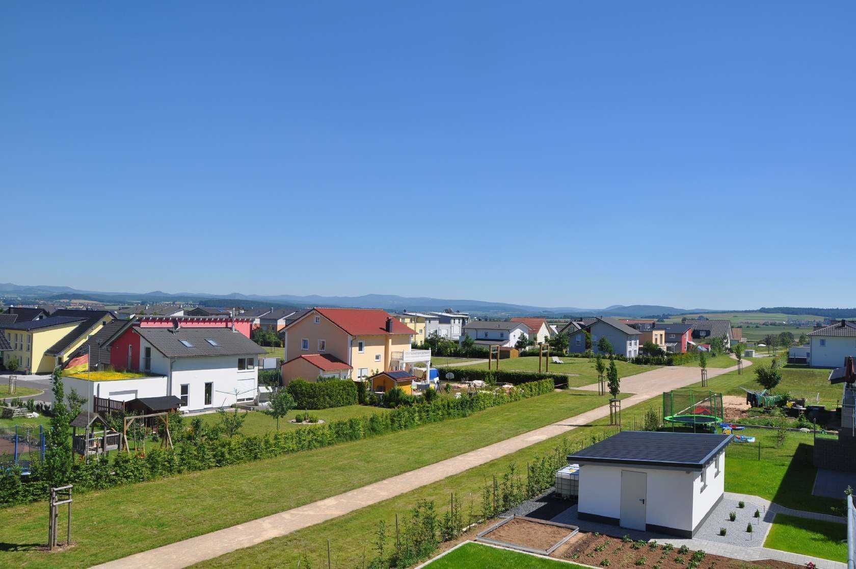 Zona residencial con casas, cielo despejado y un sendero.