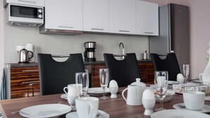 A modern kitchen with white cabinets, a microwave, a coffee maker, and a refrigerator. - Ambience apartment with terrace - modern-one | Attractive apartment w. (Fulda)