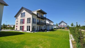 A multi-story residential building with balconies, a well-maintained lawn, and a clear sky. - Ambience apartment with terrace - modern-one | Attractive apartment w. (Fulda)
