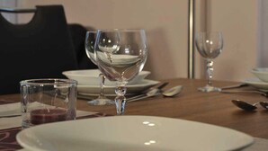 A dining table with a white plate, two wine glasses, and a candle. A painting of a rose is on the wall behind. - Ambience apartment with terrace - modern-one | Attractive apartment w. (Fulda)