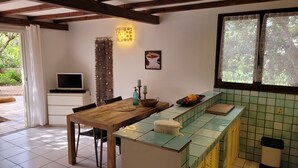 Una cocina acogedora con una mesa de madera, un televisor en un mueble y una ventana con cortinas estampadas.