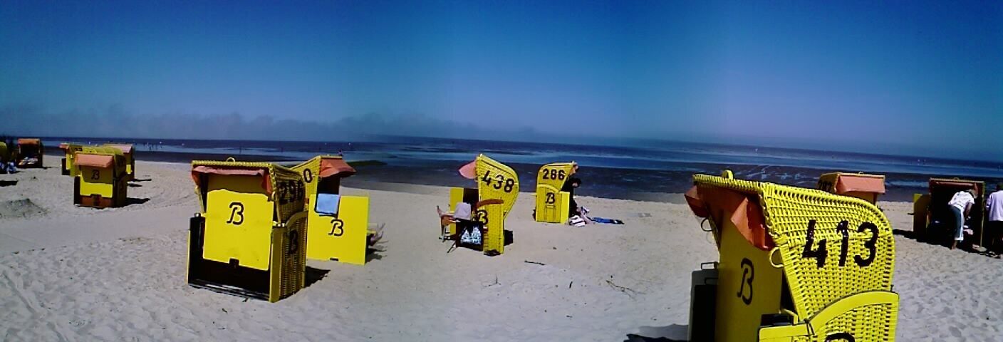 Beach huts numbered 286, 413, and 3 on a sandy beach with the ocean in the background.