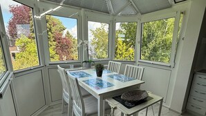 A conservatory with a table, chairs, and a small cart. - Top apartment with 2 bedrooms, balcony and internet flat rate (Grömitz)