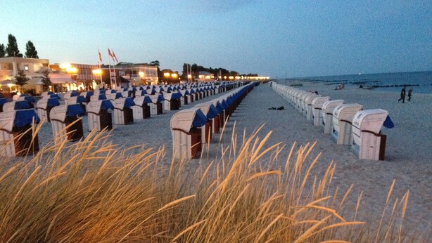 A beach with rows of beach huts and a row of buildings in the background. - Top apartment with 2 bedrooms, balcony and internet flat rate (Grömitz)