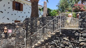 Una escalera de piedra lleva a un edificio con fachada blanca y contraventanas marrones. Un letrero dice "Casa Verano".