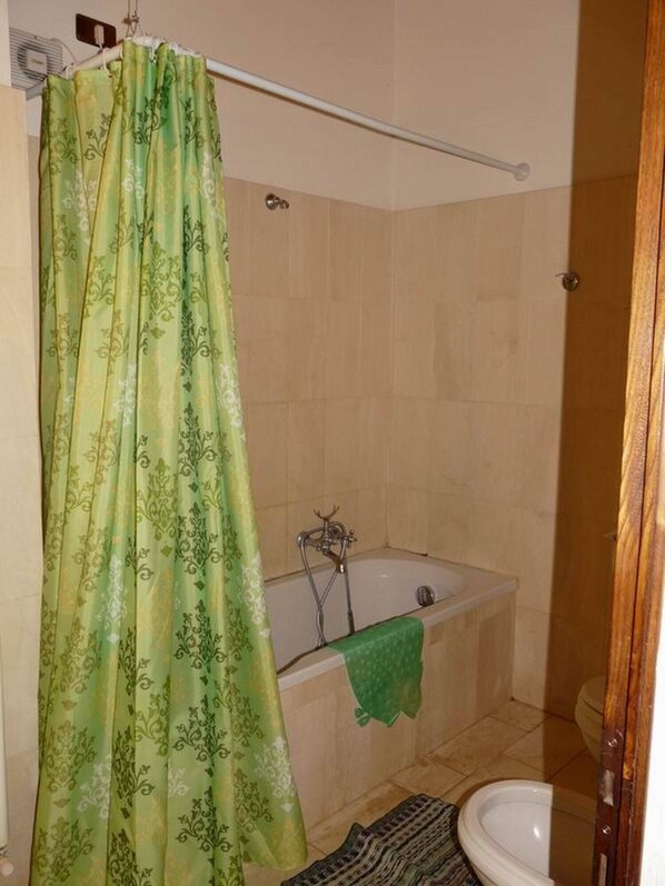 Un baño con bañera, inodoro y cortina de ducha.