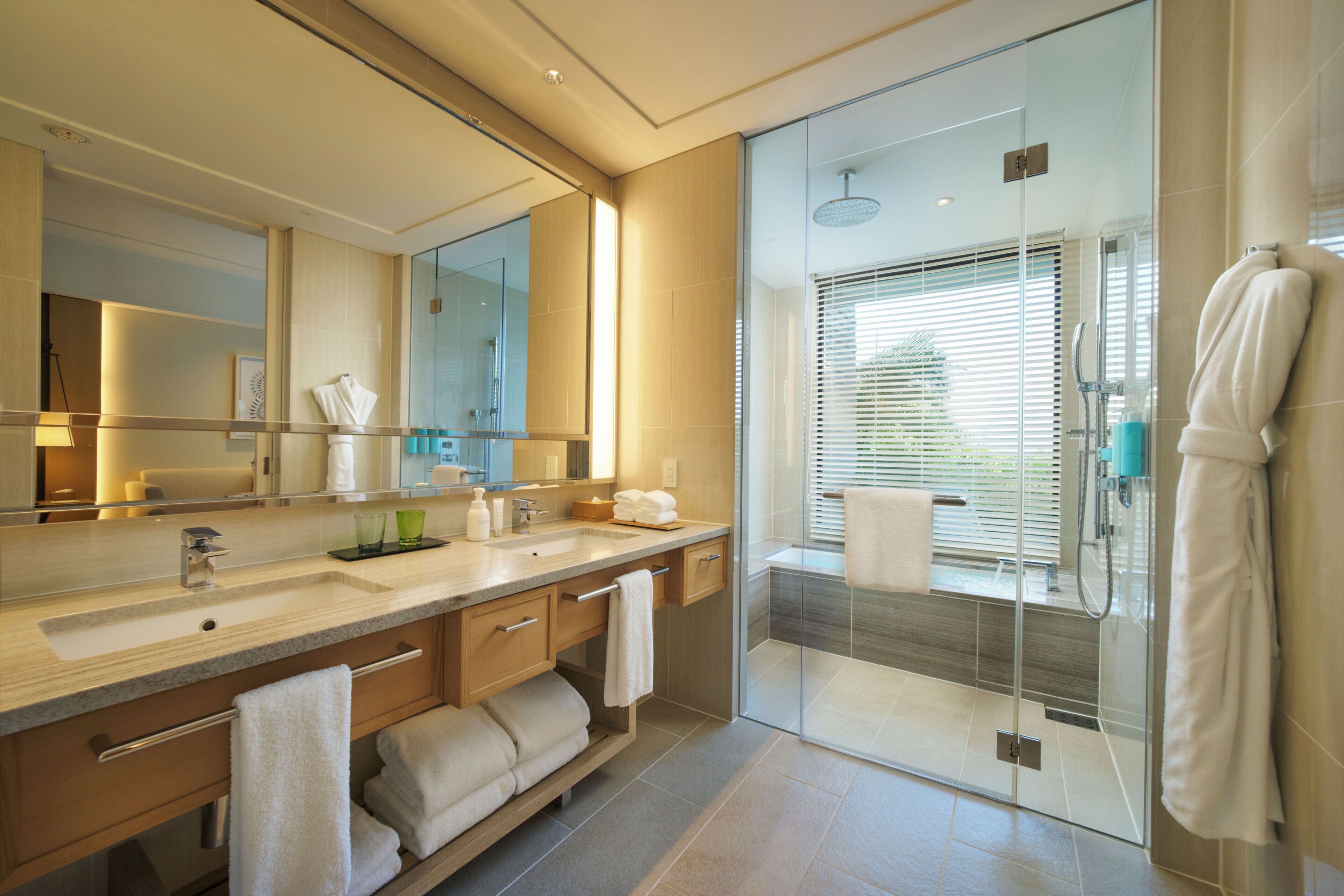 Une salle de bain moderne avec une douche à parois de verre, un grand miroir et un meuble-lavabo doté d’un évier et d’un porte-serviettes.