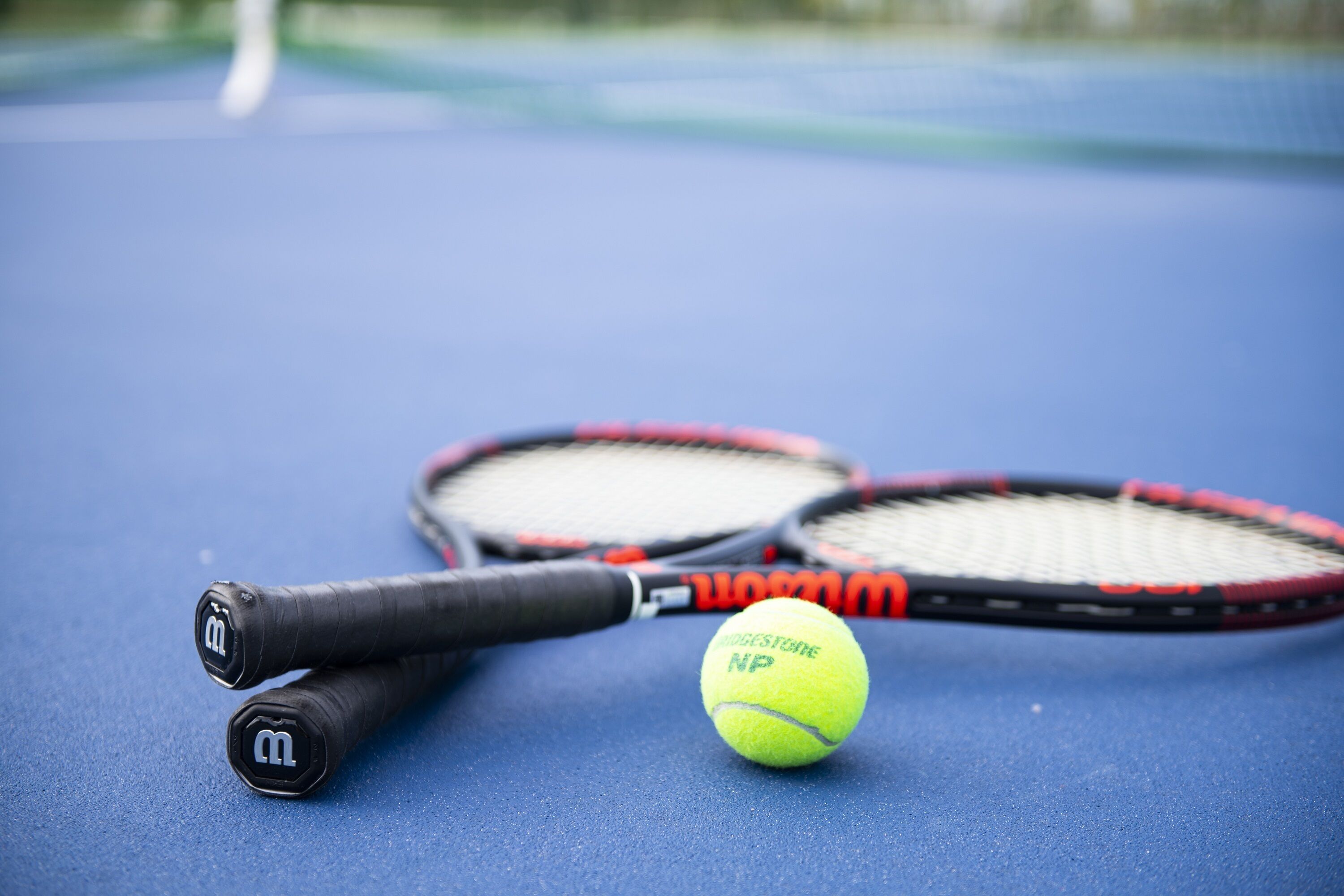 A tennis racket and ball on a blue surface.
