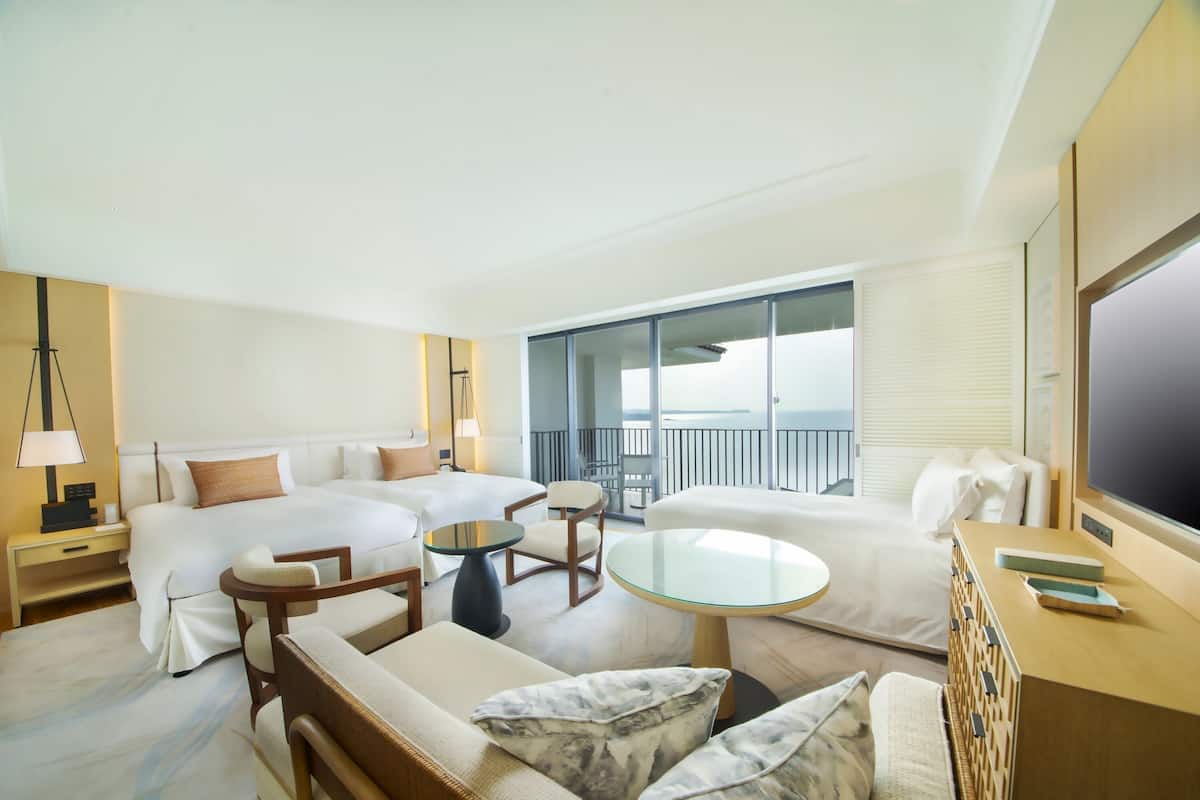 A modern hotel room with a large bed, two sofas, a round table, and a TV.