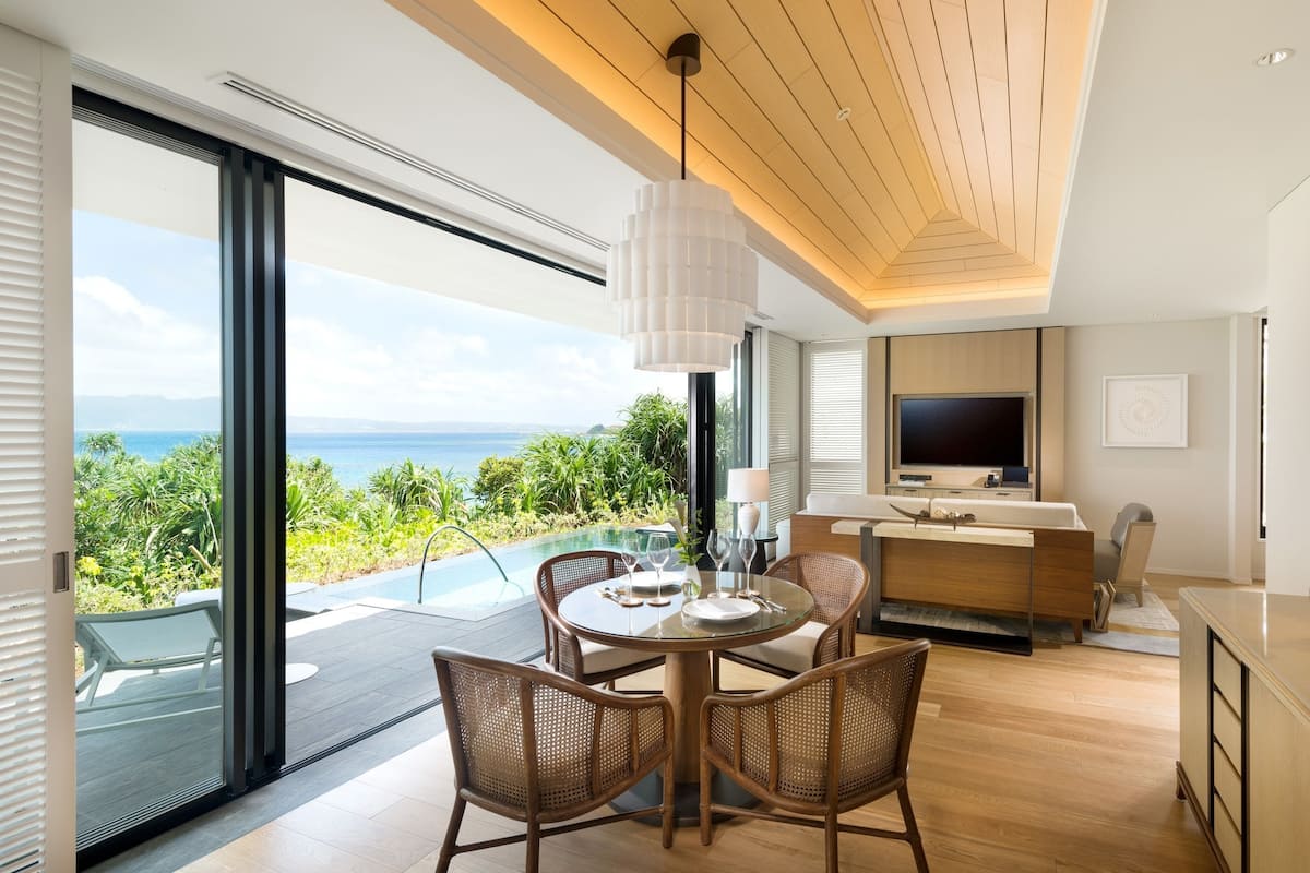 A modern living room with a large glass door leading to a balcony overlooking the ocean.