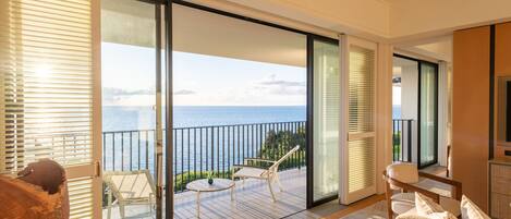Un balcón con vista al mar, amueblado con una mesa y sillas, y una escultura de madera.