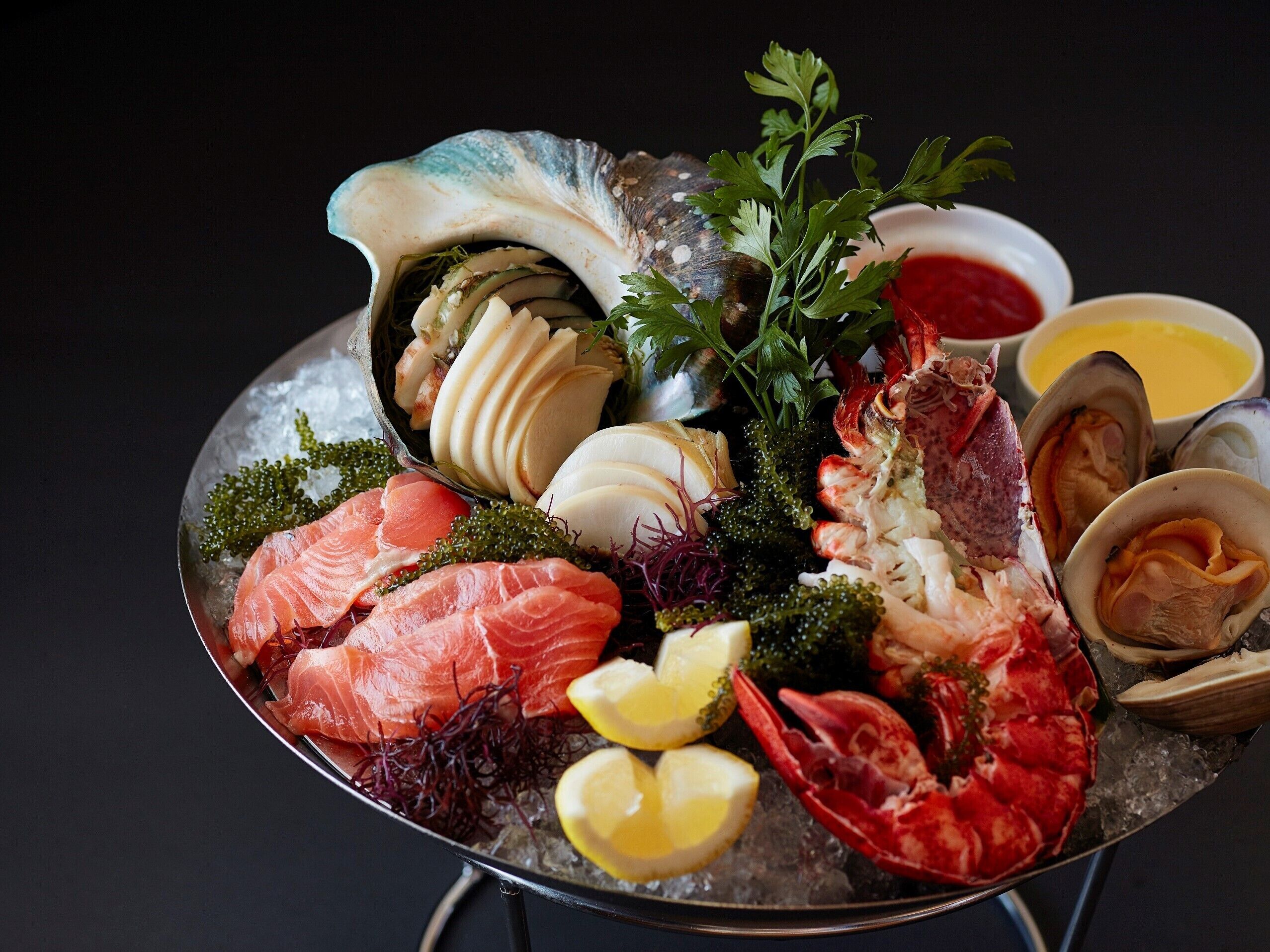 A seafood platter with various types of fish, shellfish, and garnishes on a bed of ice.