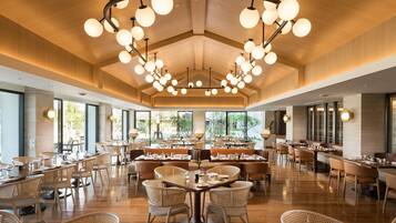 A spacious restaurant with high ceilings, modern chandeliers, and a mix of seating arrangements including tables and booths.