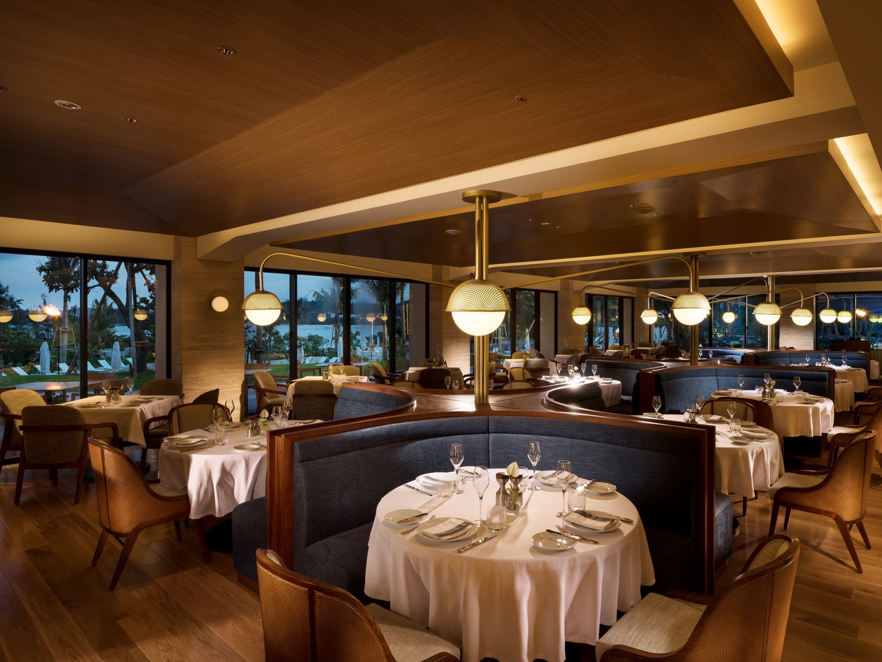 Een restaurant met ronde tafels, zitjes en uitzicht op het omliggende landschap.