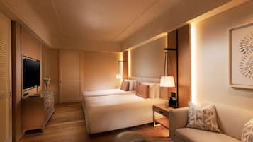 Una habitación de hotel con dos camas, televisión, escritorio, sofá y una mesita.
