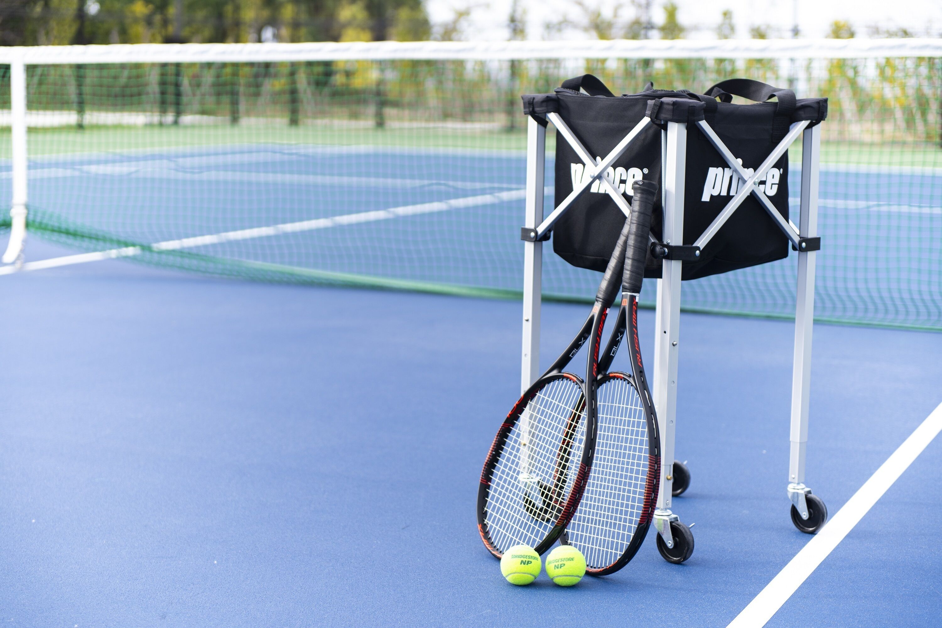 Una cancha de tenis con una red, dos raquetas y dos pelotas.
