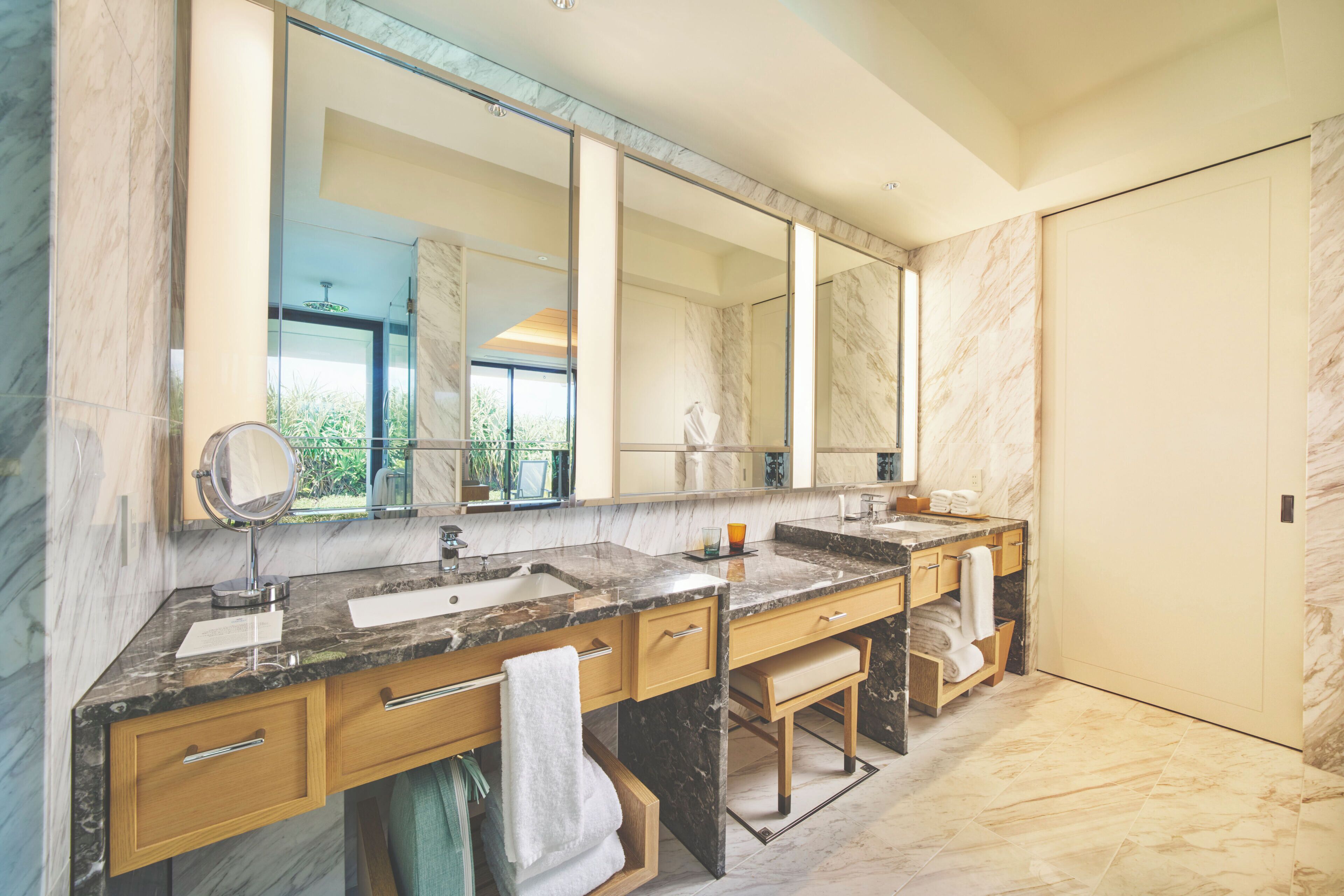 A modern bathroom with marble countertops, dual sinks, and a large mirror.
