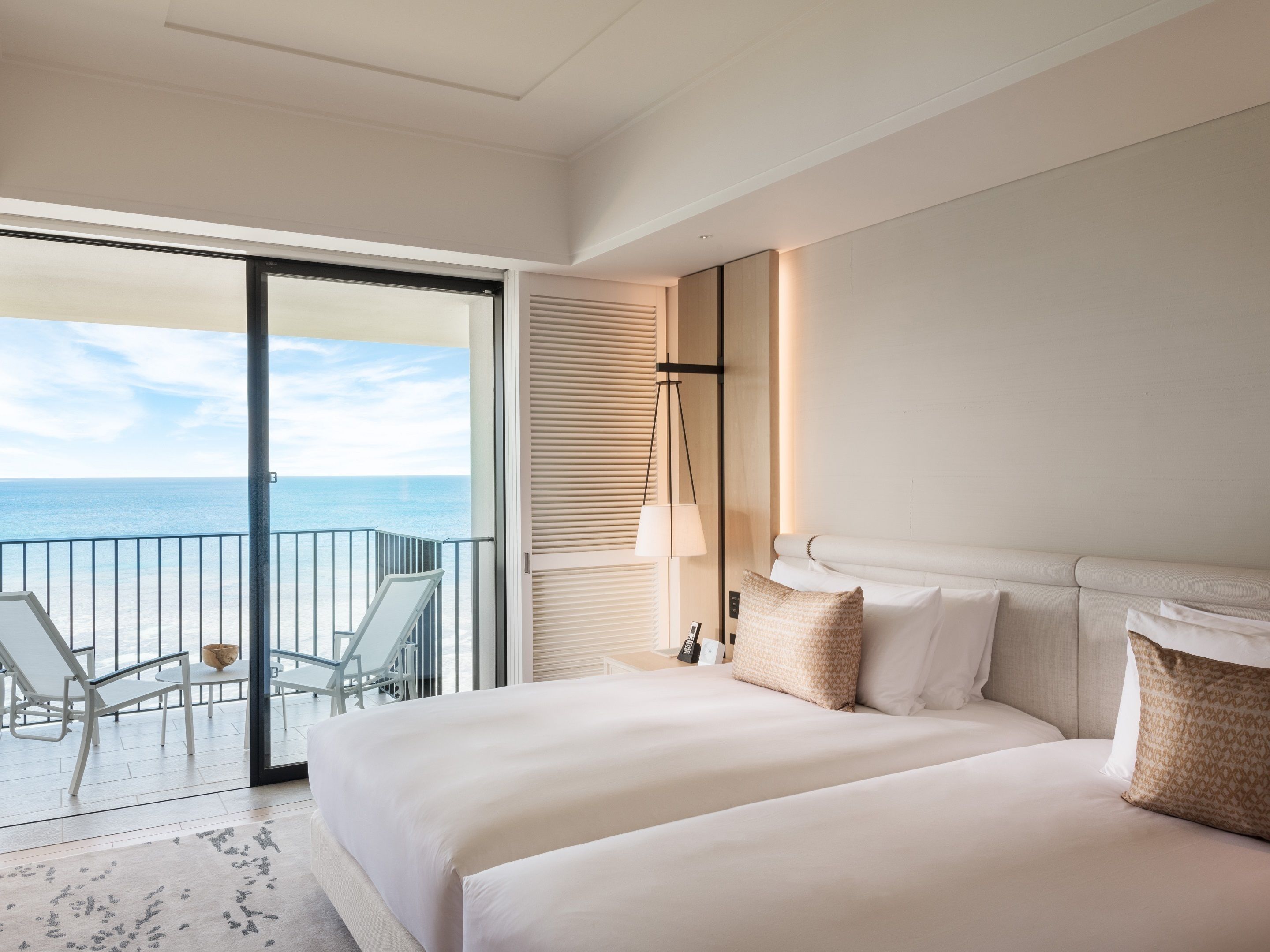A hotel room with a balcony, a bed, and a view of the sea.