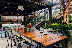 A restaurant with a wooden table, chairs, and a staircase. - Savv Hotel (George Town)