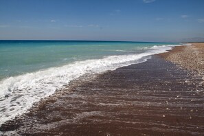 A beach with clear turquoise water and a pebbly shoreline. - Country house in the olive grove with breathtaking views for every season (Messinia)