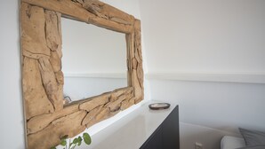 Une pièce moderne avec un miroir rustique à cadre en bois, un mur blanc, un meuble noir et un canapé gris.