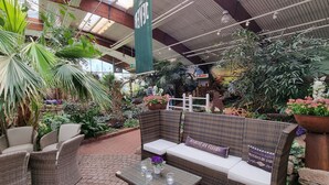 Ein Wintergarten mit Korbmöbeln, Blumentöpfen und einer Steinwand.