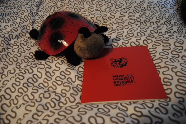 A plush toy and a red card with text on a patterned surface. - Lovingly furnished ground floor apartment - second home for families and Frisians (Carolinensiel)