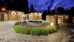 Un edificio de estilo cabaña de madera con una estructura circular, un área de patio con bancos y un sendero de piedra.