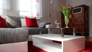 Una sala de estar moderna con un sofá, una mesa de centro de vidrio y una alfombra roja.