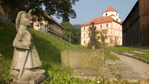 Una estatua de piedra en un área con césped y un edificio al fondo.