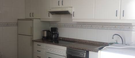 A compact kitchen with white cabinets, a coffee maker, a dishwasher, and a sink.