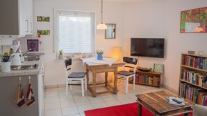 Un espacio habitable pequeño con kitchenette, comedor y televisor.