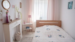 Un dormitorio con una cama de madera, un escritorio blanco, un espejo y una chimenea.