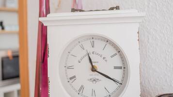 Une horloge blanche avec des chiffres romains et le nom de la marque inscrit sur le cadran, posée sur une surface en bois.