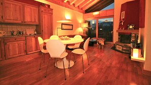 A modern kitchen with wooden cabinets, a dining table with chairs, and a fireplace. - Stylish loft with a great panoramic view (Veysonnaz)