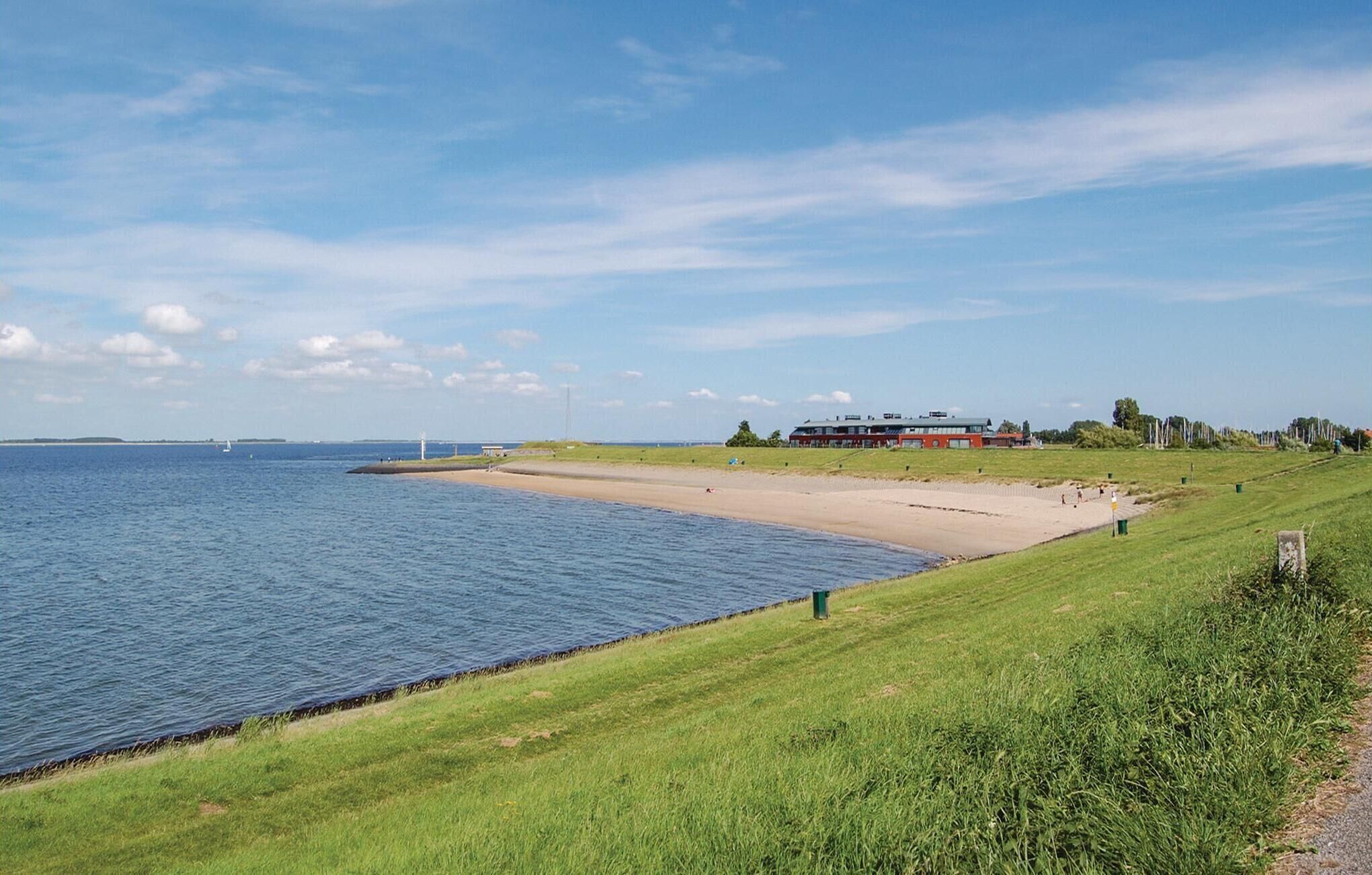 Une vue sur la côte, avec une zone herbeuse, une plage de sable et un bâtiment doté d’un toit rouge, situé près de l’eau.