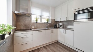 Una cocina moderna con armarios blancos, electrodomésticos de acero inoxidable y una ventana con una planta.