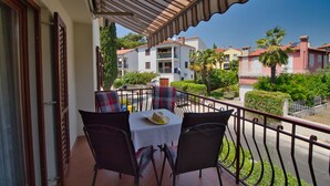 Un balcón con una mesa y sillas, con vista a una zona residencial con casas y follaje.