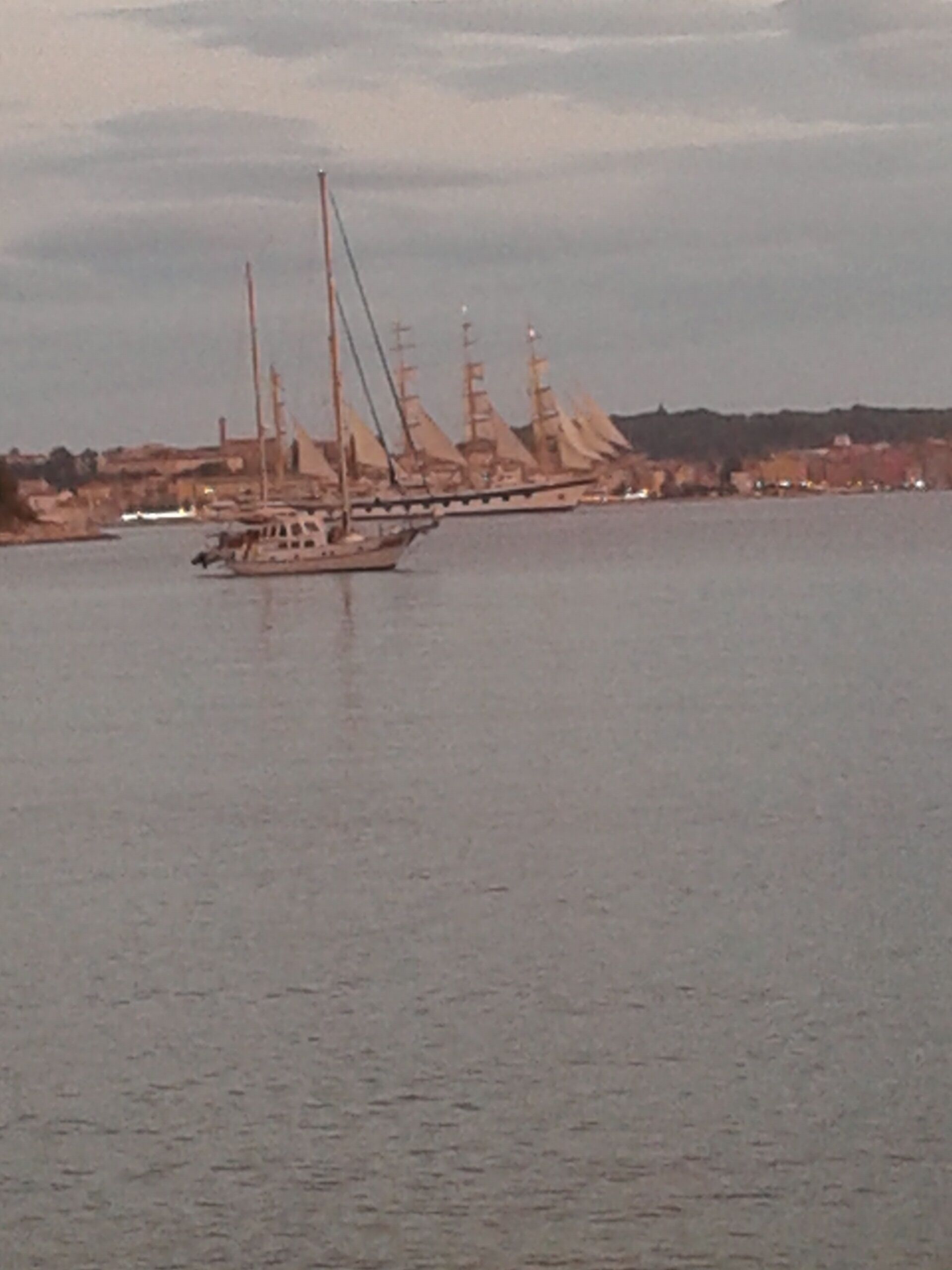 A large sailing ship with multiple masts and sails on a calm body of water.