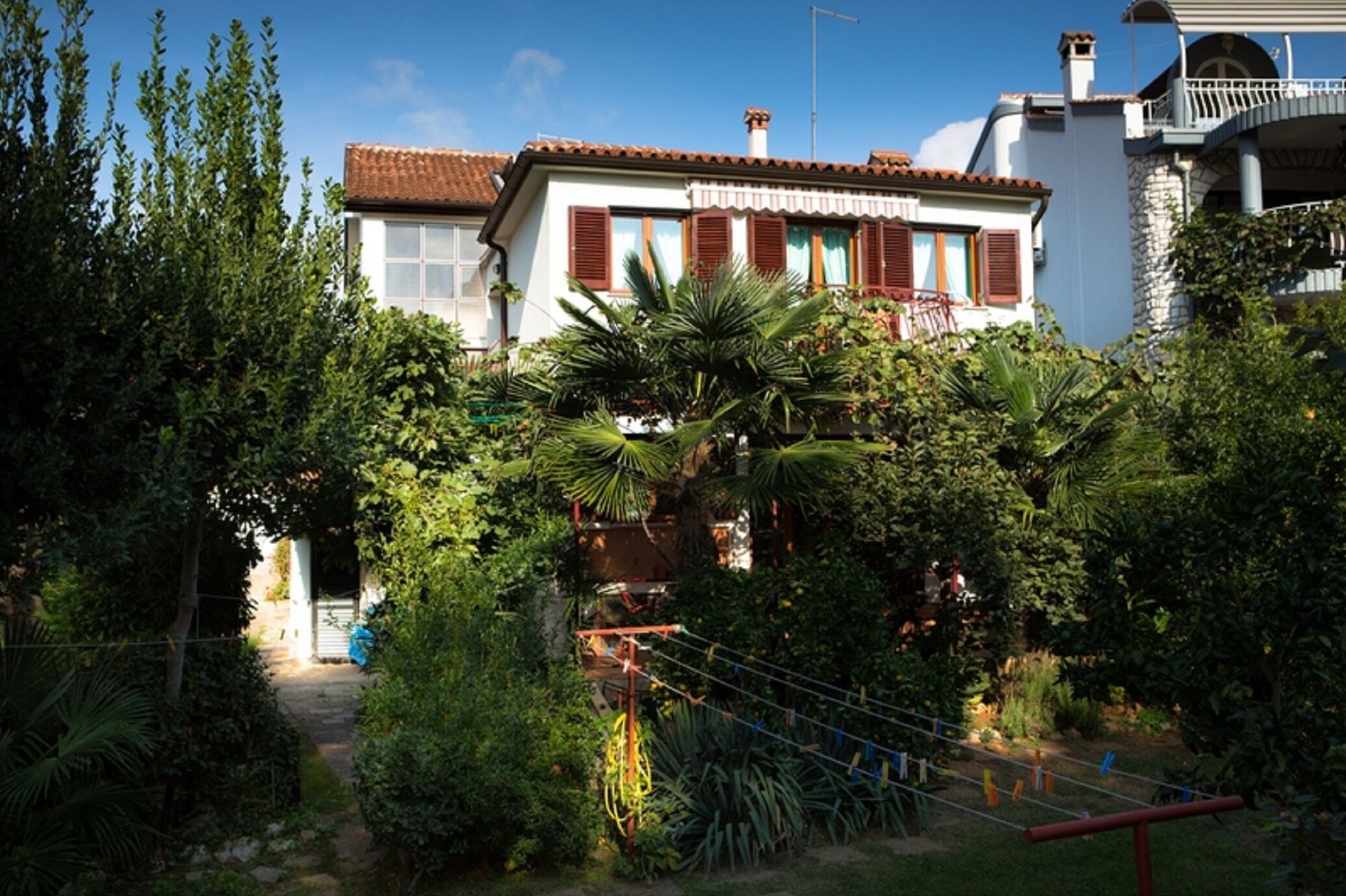 Una casa con jardín, balcón y una escalera que lleva a la entrada.