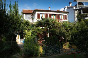 Ein Haus mit Garten, einem Balkon und einer Treppe, die zum Eingang führt.