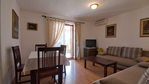 Una sala de estar con sofá, mesa de centro, televisor y zona de comedor con mesa y sillas.