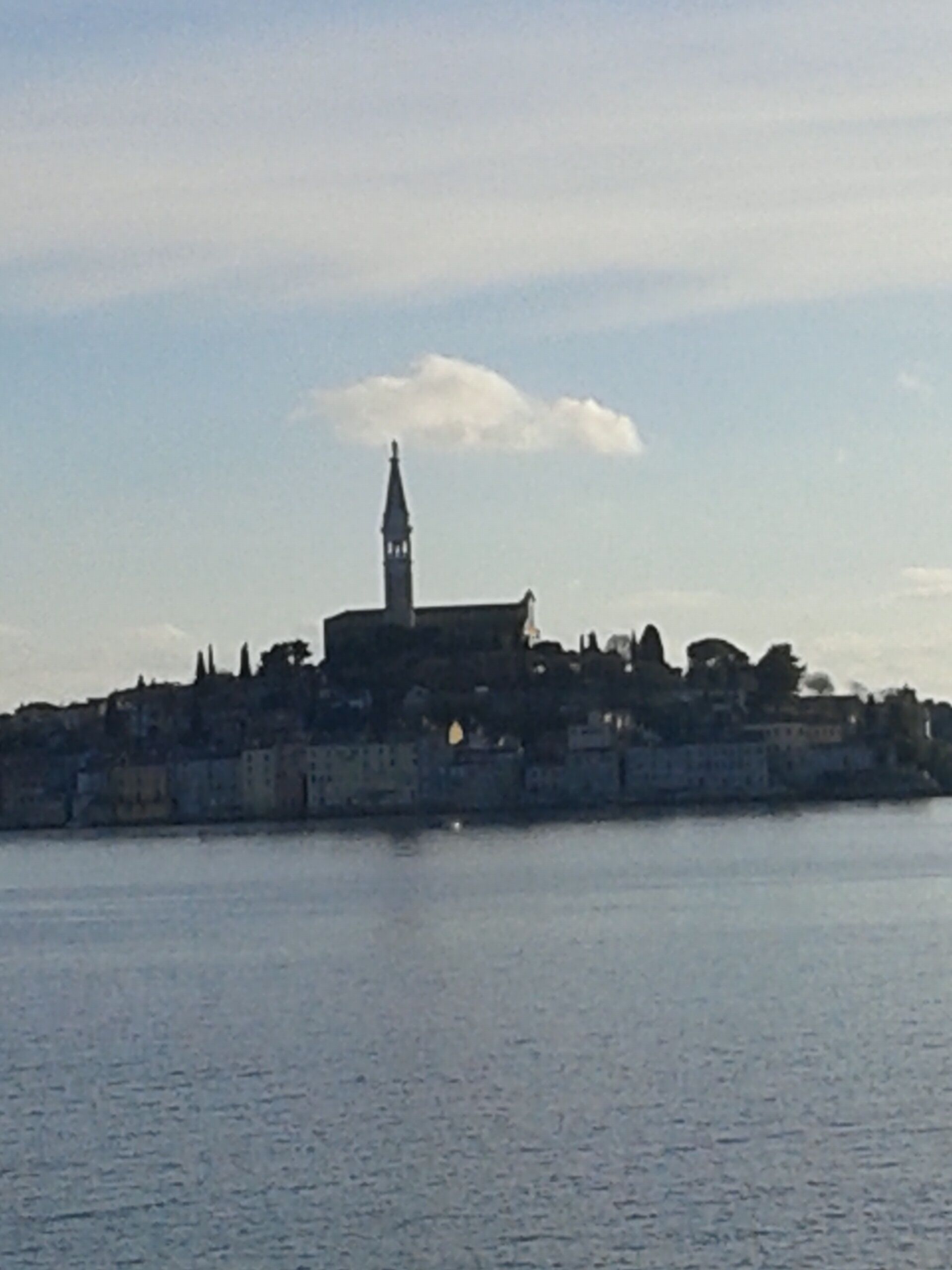 A historic building with a prominent tower, situated by a calm body of water.