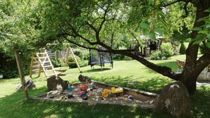 Une aire de jeux avec un bac à sable, des balançoires et une structure d’escalade.