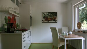 Una cocina con una mesa de comedor, sillas, un radiador y una ventana con vistas a árboles.