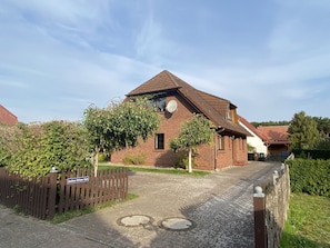 A brick building with a sloped roof, a satellite dish, and a gated entrance. - Maximum comfort, yet family-friendly (Glowe)