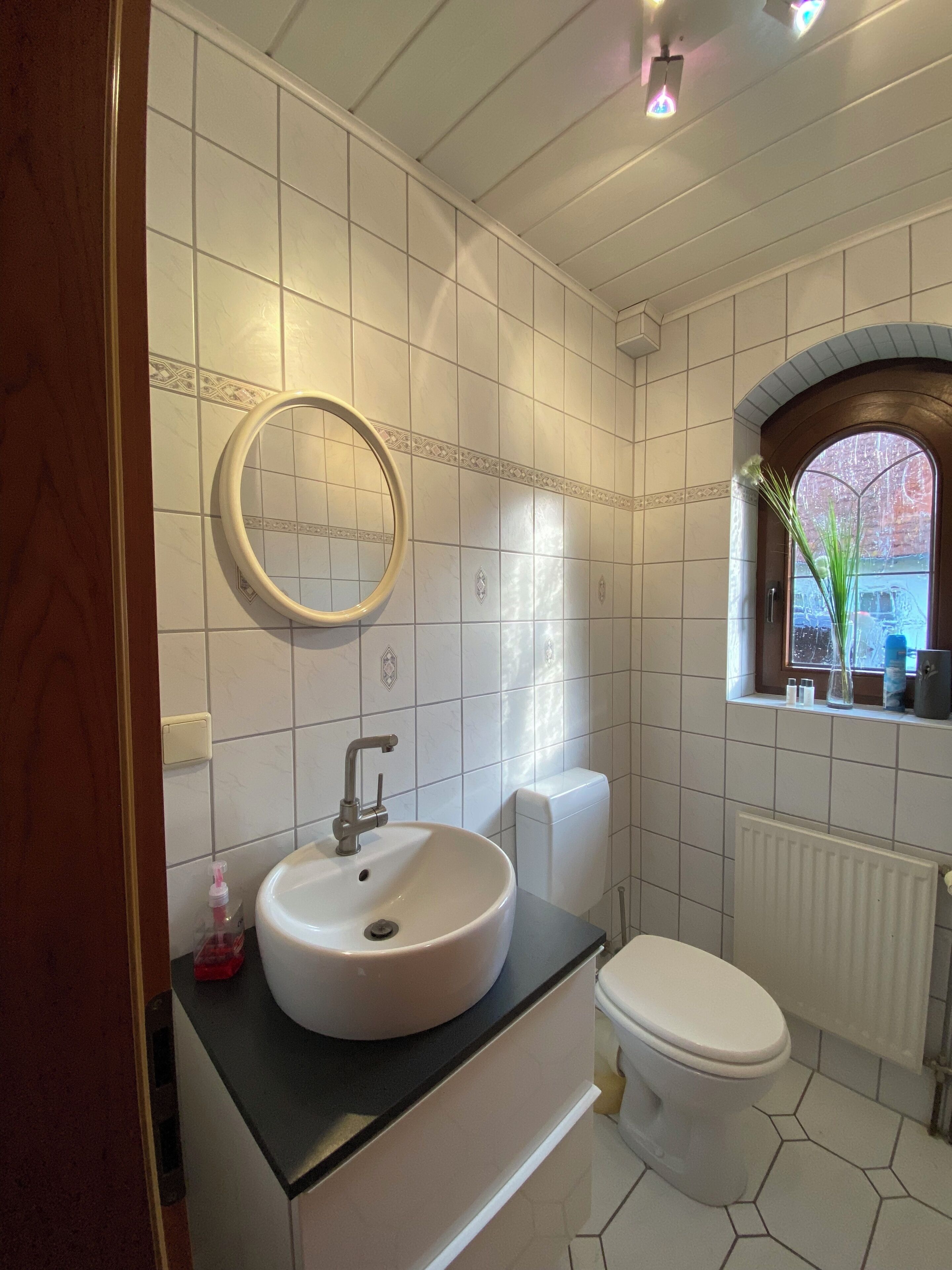 A bathroom with a sink, toilet, and a window with a view.